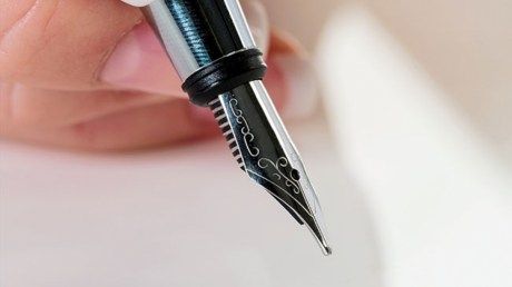 eine Hand hält einen Füllfederhalter um zu schreiben