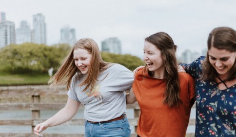 Drei junge Frauen lachend Arm in Arm